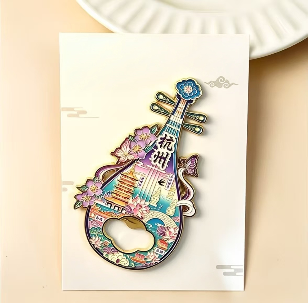 Metal bottle opener refrigerator magnet in pipa shape, decorated with scenery patterns of Hangzhou West Lake, Leifeng Pagoda, Broken Bridge and other iconic attractions. Ideal tourist souvenir and traditional Chinese cultural gift.