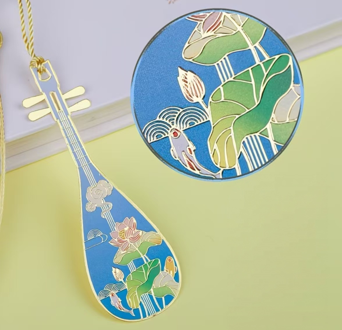 Detail of pipa‑shaped metal bookmark, spray‑print coloring craft, delicate lotus and koi fish pattern, Chinese cultural stationery souvenir